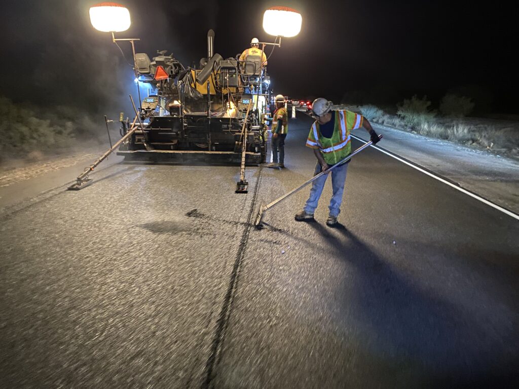 A man is working on a road at night.