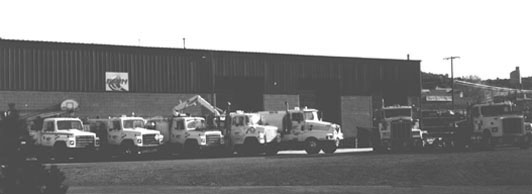 A black and white photo of several trucks parked in front of a building showcasing Fann Contracting's operations.