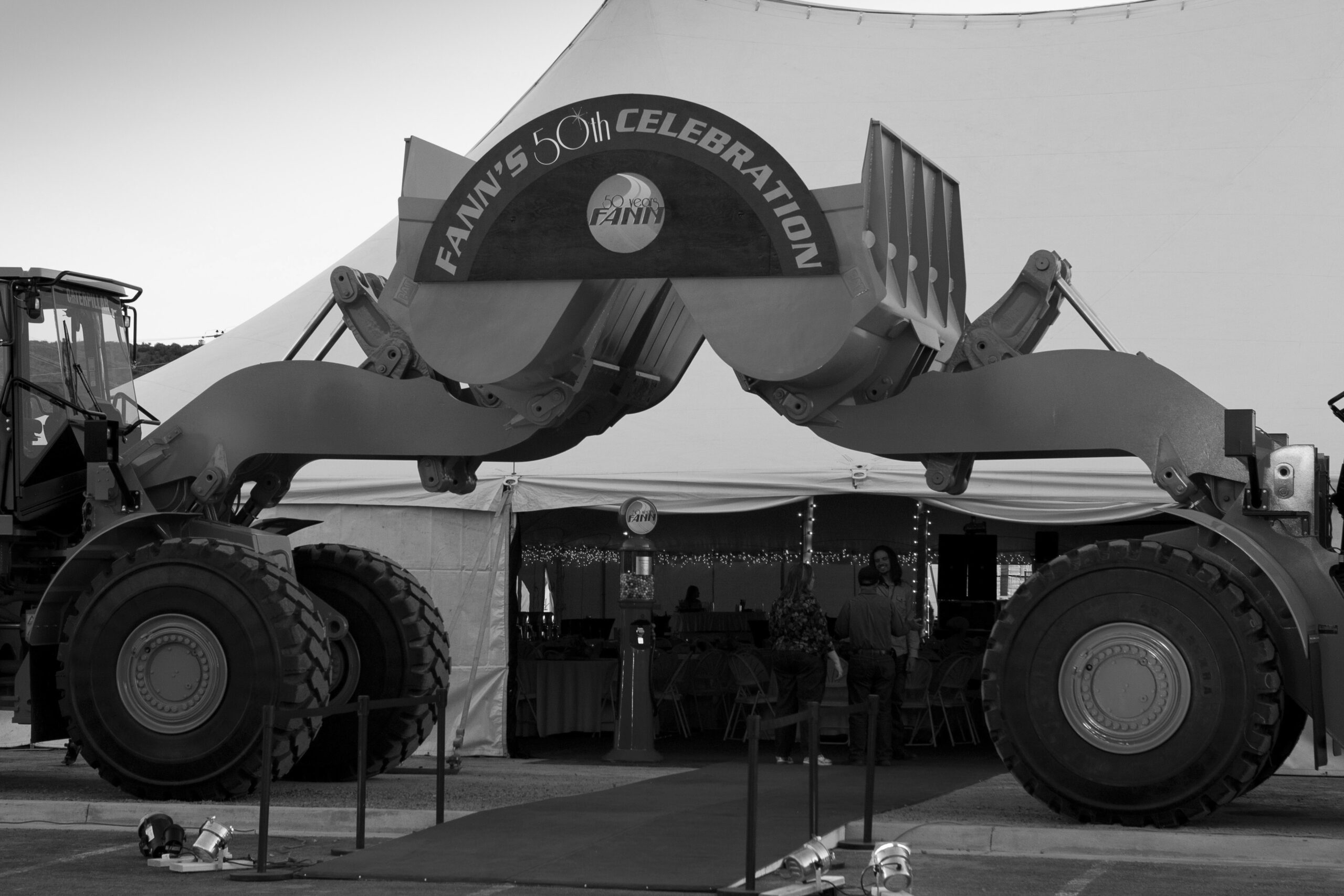 A black and white photo of a large tractor in front of a tent, pertaining to Fann Contracting.