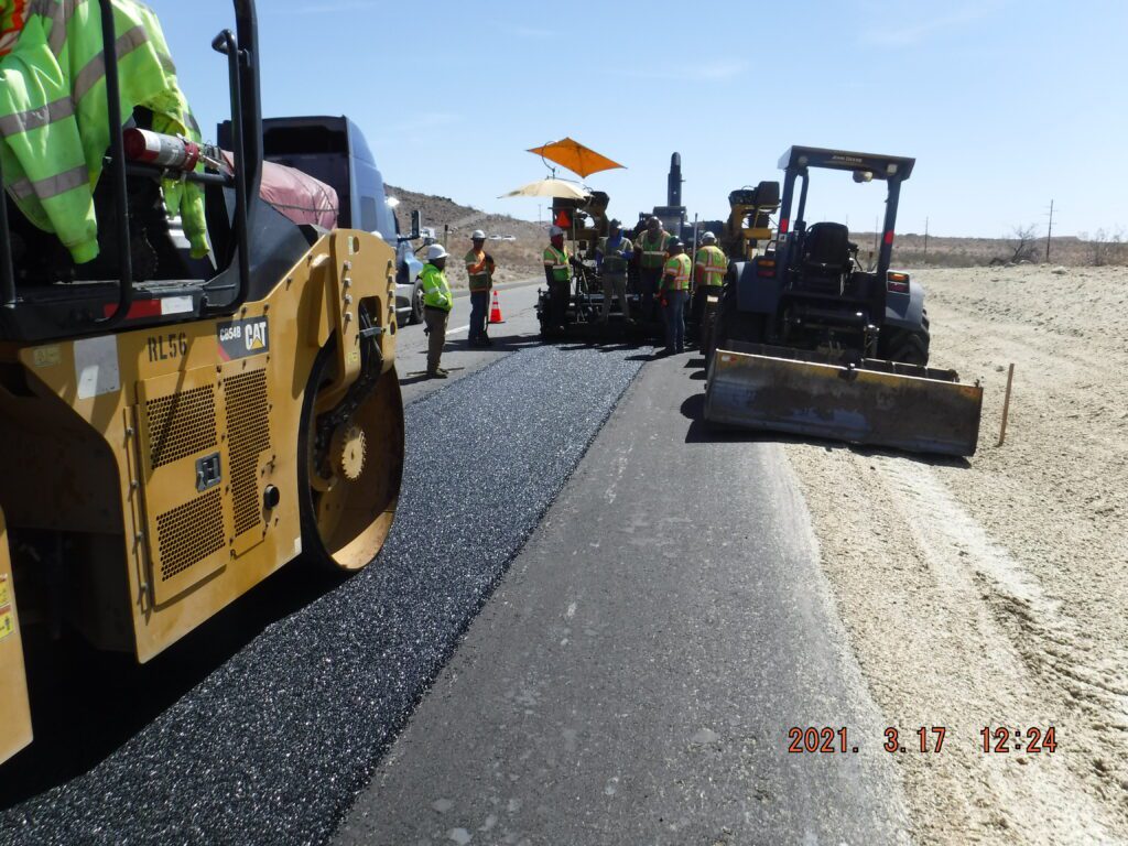 A group of workers are working on a road in the desert.
