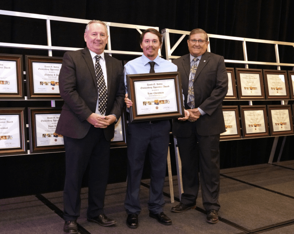 Three men standing in front of a framed plaque.