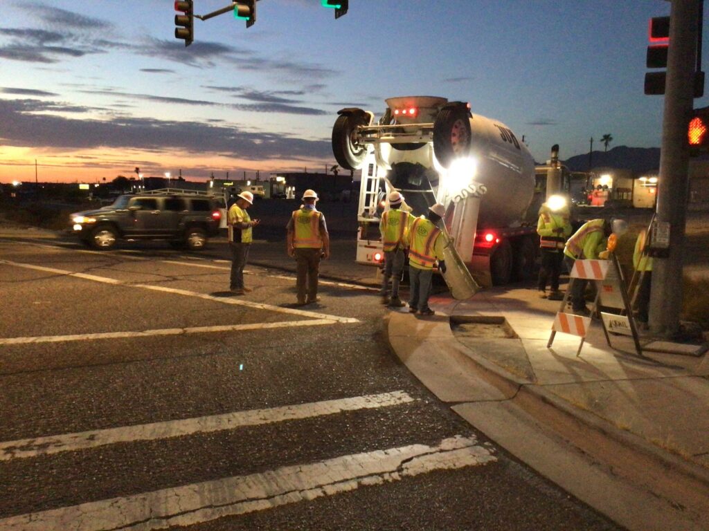 A group of workers standing at a traffic light.