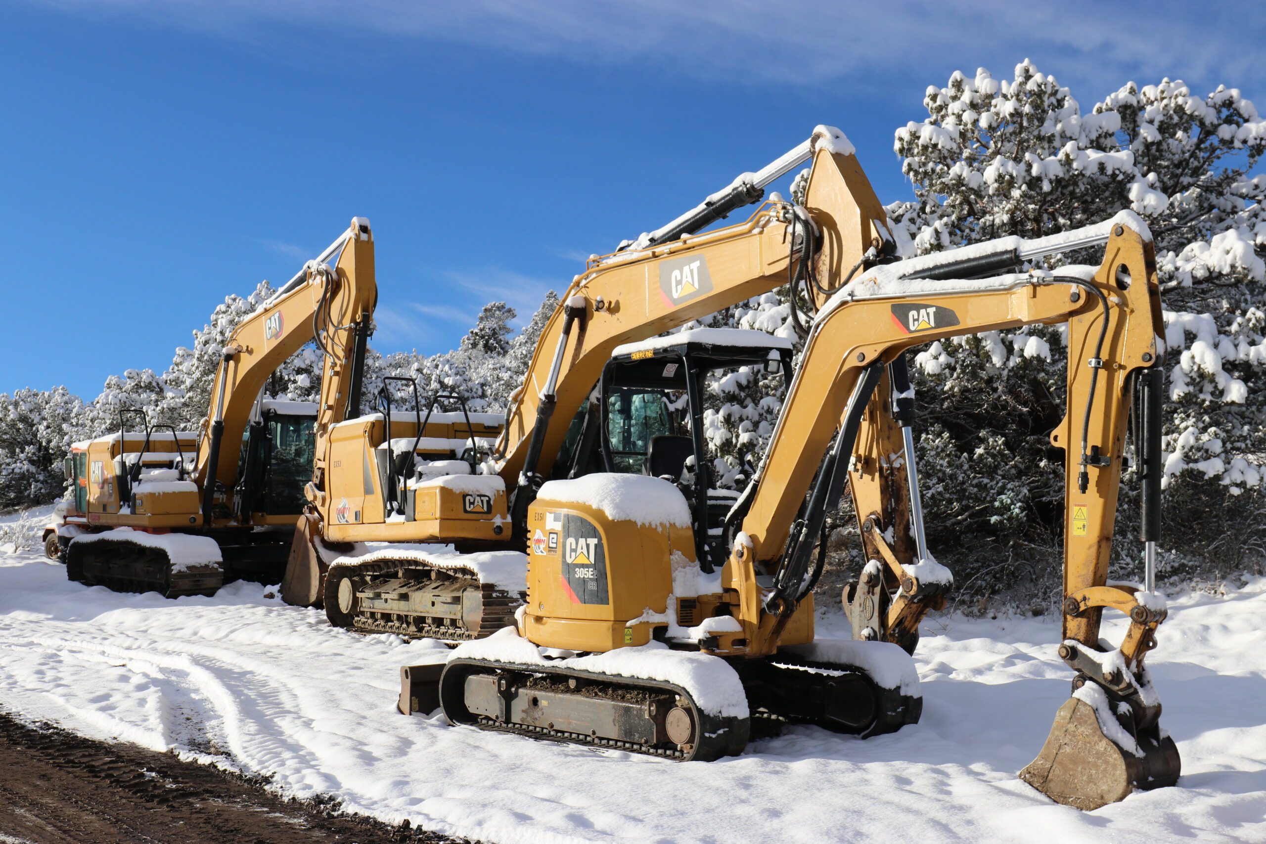 Caterpillar excavators parked on a snowy road.
