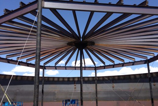 A large metal structure is being built under a blue sky.