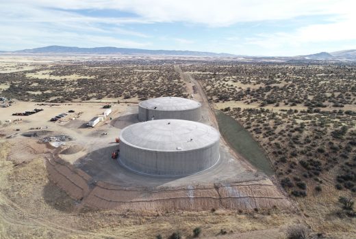 An aerial view of two large concrete tanks in the desert.