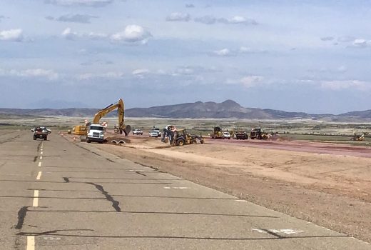A construction crew is working on a runway in the desert.