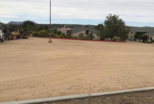 A dirt parking lot with a bulldozer parked in it.