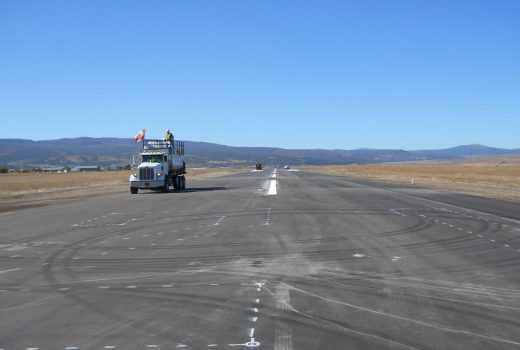 A truck is driving down an airport runway undergoing Phase V rehabilitation.