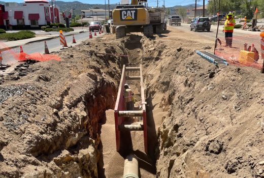 A construction crew is working on Phase 2C of the Sundog Trunk Main in the street.