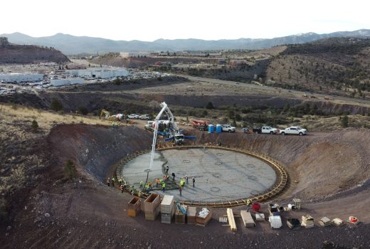 An aerial view of a construction site with a large hole in the ground undergoing Zone 56 1.5 MG Water Tank and Pipeline installation.