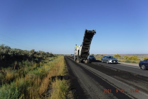 A truck is laying asphalt on a road.