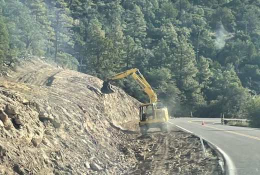 A bulldozer is working on a road in the mountains.