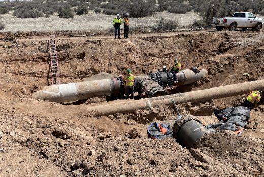 A group of workers are working on a pipe at a CMAR Water Production Facility.
